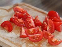 トマトをスライスし、ツィビュールとオリーブを添えて準備するプロセス
